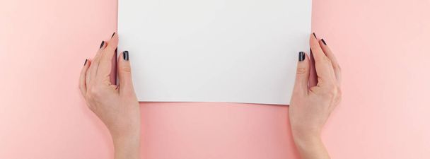 創造的なフラットに横たわっていた女性の手の上から見る黒いマニキュア空 A4 用紙ページ モックとパステル千年ピンク ペーパー バック グラウンド コピー空間。ブログをレタリング テキストの概念テンプレートを書く最低限 - 写真・画像