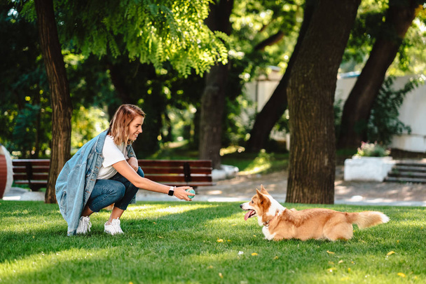 Portret van vrouw met hond Welsh Corgi Pembroke in dog park - Foto, afbeelding