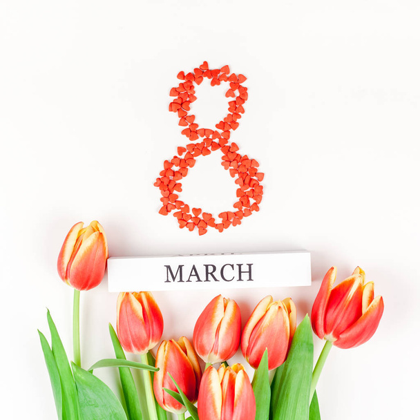 Creative flat lay top view 8 March International Women's Day greeting card with red tulips spring flowers on white background. Celebration Postcard template - Photo, Image