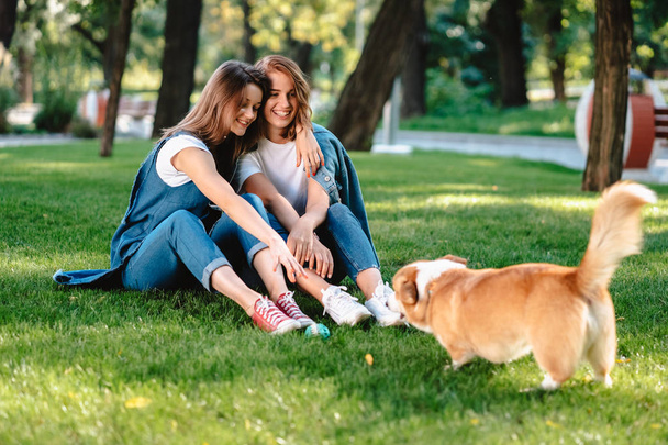 Zwei Freundinnen im Park spielen mit kleinem Hund - Foto, Bild