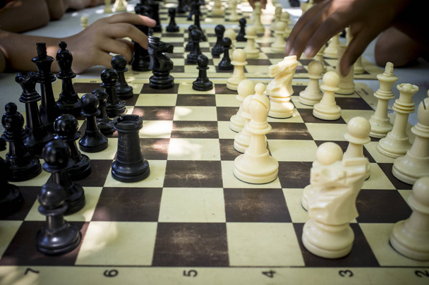 Εκπαιδευτικό σεμινάριο σκάκι για παιδιά κάτω από σκιές δέντρων καλοκαίρι. Multirracial παίκτες - Φωτογραφία, εικόνα