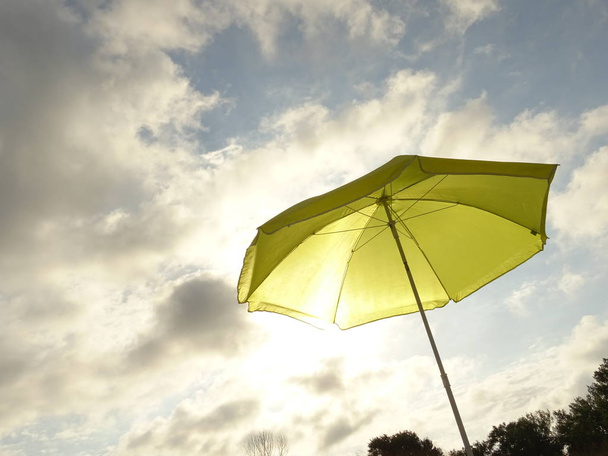 Yellow Sun Umbrella against the Background of the Blue Sky - Foto, imagen
