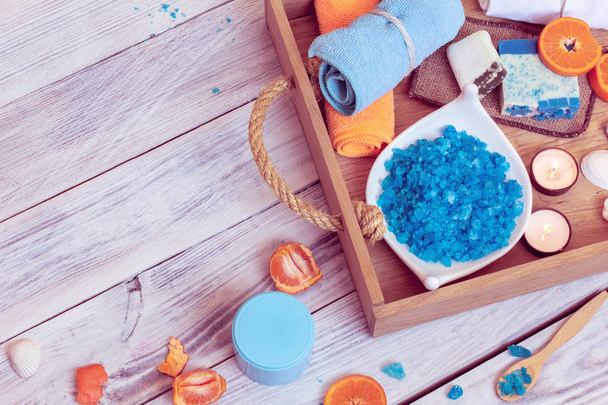 SPA consist from towels, blue sea salt, candles and tangerines in a wooden tray - Photo, image