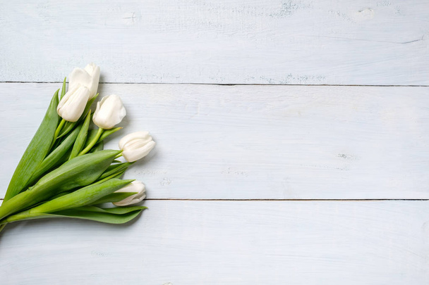 bunch of white tulips on blue wooden table. Banner mockup card with copy space for congratulation, woman or mother day, easter, spring holiday, birthday - Valokuva, kuva