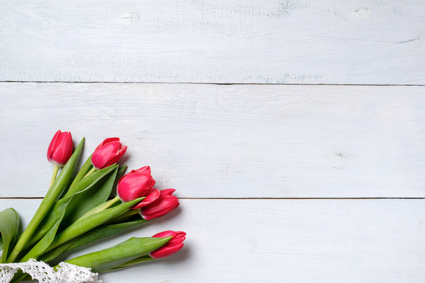 bunch of red tulips on blue wooden table. Banner mockup card with copy space for congratulation, woman or mother day, easter, spring holiday, birthday - Fotografie, Obrázek