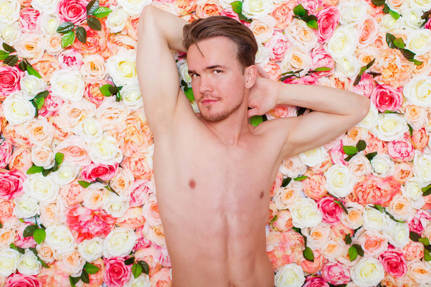 Portrait of a young sexy guy on the background of floral studio wall - Fotoğraf, Görsel