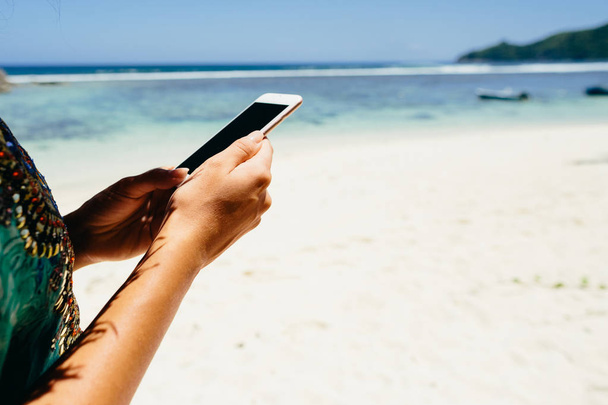 жінка за допомогою смартфона на пляжі в тропіках. Самка подорожувати і використовувати смартфон на пляжі Сейшельські острови. - Фото, зображення