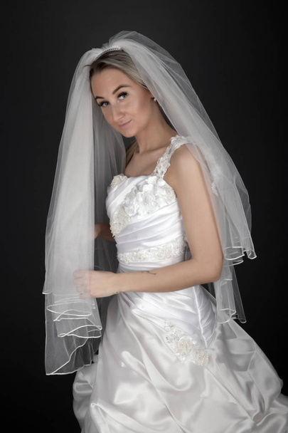 Beautiful blonde bride in a white dress on a black background - Photo, image