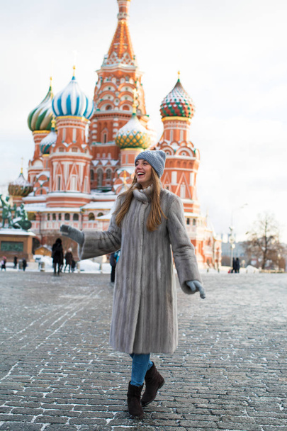 Portrait of a young woman in a blue knitted hat and gray mink coat, posing in winter Red Square in central Moscow - Foto, immagini