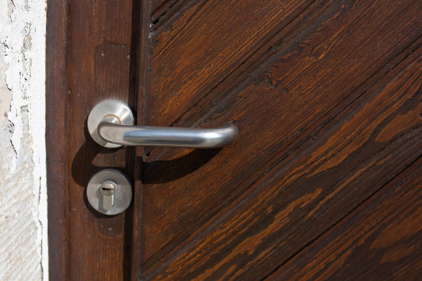 Tirador de puerta plateado y cerradura de una puerta de madera marrón. Copiar espacio
 - Foto, Imagen