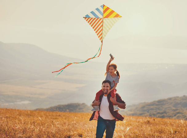 счастливая семья отец и ребенок дочь запустить воздушного змея на Meado
 - Фото, изображение