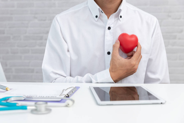 Heart disease concept, Doctor holding red heart ball in clinic. - Photo, Image