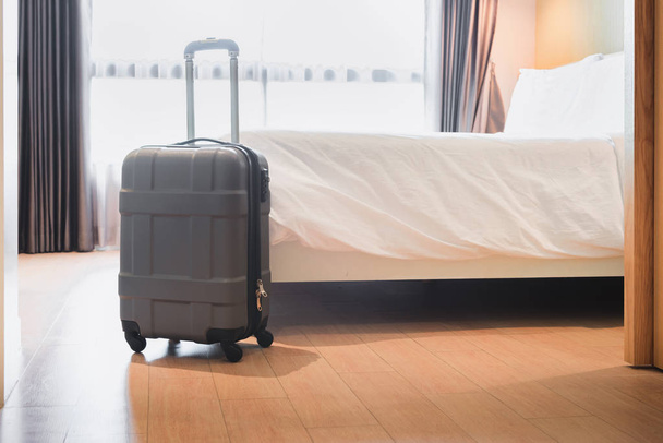 Ταξιδιού αποσκευών του ταξίδι διακοπές στο ξενοδοχείο υπνοδωμάτιο, άνετο κρεβάτι στο σύγχρονο εσωτερικό θέρετρο με βαλίτσα για ταξίδι διακοπών, ταξιδεύουν τσάντα και τουριστικά έννοια. - Φωτογραφία, εικόνα