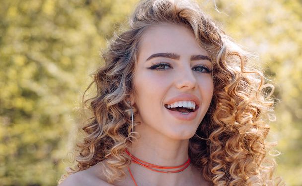 Outdoors portrait of beautiful young girl laughing. Pretty girl with curly hair. - Valokuva, kuva