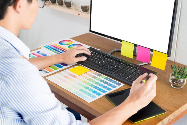 Grafika, projektanta lub creative gospodarstwa myszy i zrobić jego pracy tworzywo kolor pantone swatch próbek sztuki narzędzi na biurku w biurze  - Zdjęcie, obraz