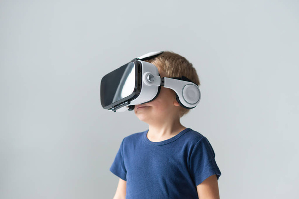 Portrait of happy boy in a virtual reality headset. Attractive kid using vr goggles at home. Entertainment technology, futuristic gadgets and generation Z concept. - Zdjęcie, obraz