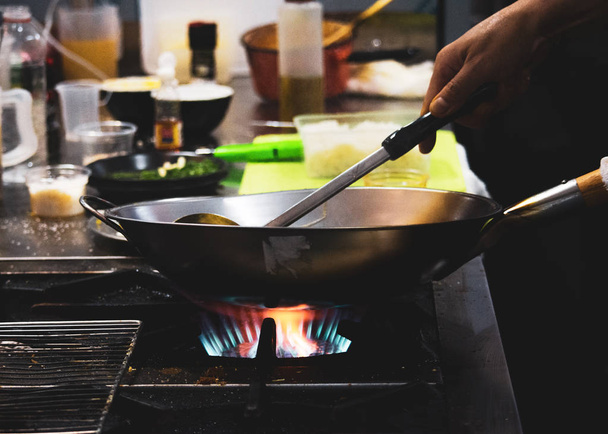 台所では、シェフの料理は鍋に野菜炒めをかき混ぜる - 写真・画像