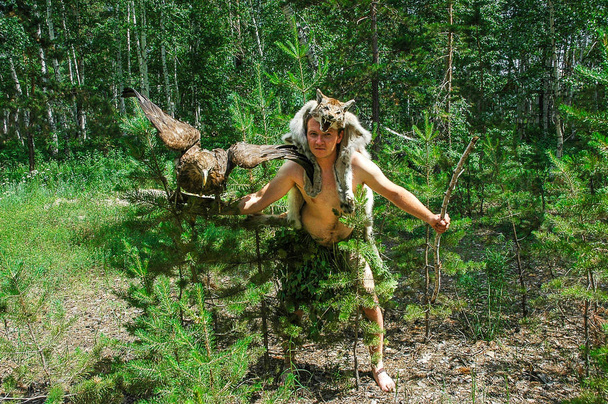 hombre primitivo en la caza del bosque con sentado en el brazo de un águila y una piel de lince
 - Foto, Imagen