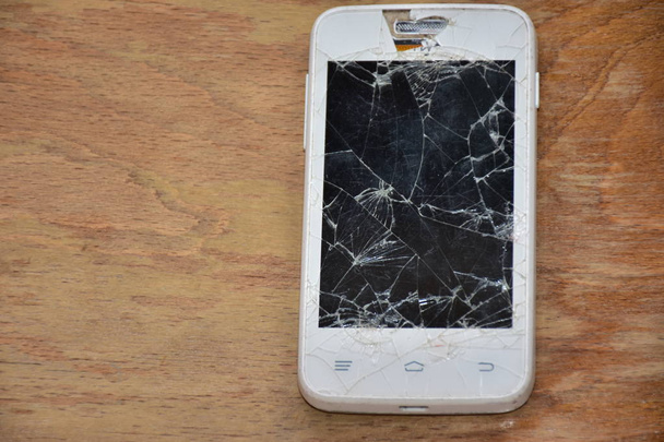 uszkodzony telefon na drewnianym tle - - Zdjęcie, obraz