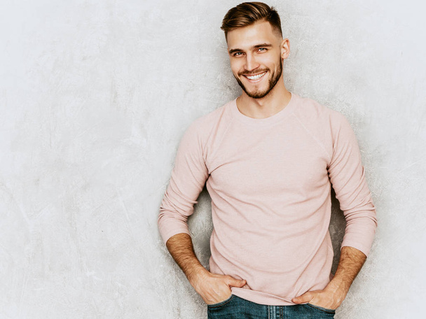 Portret przystojny uśmiechający się hipster lumbersexual biznesmen model sobie codzienne letnie różowe ubrania. Moda stylowy mężczyzna pozowanie ścianę szary - Zdjęcie, obraz