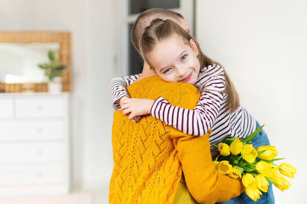 Happy Mother's Day or Birthday Background. Adorable young girl surprising her mom, young cancer patient, with bouquet of yellow tulips. Family celebration concept. - Fotoğraf, Görsel