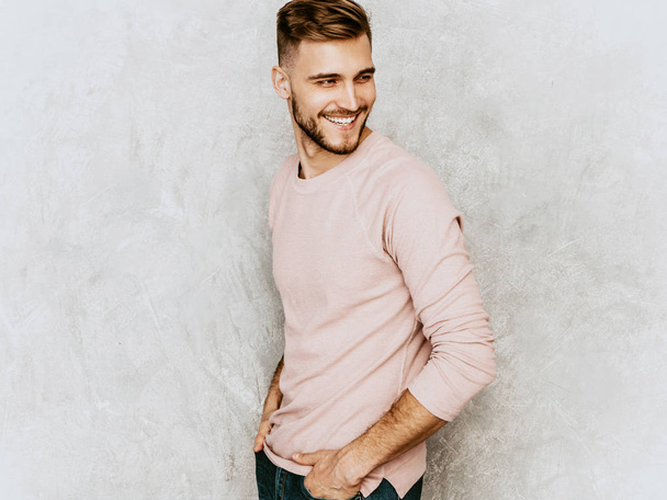 Portrait of handsome smiling hipster lumbersexual businessman model wearing casual summer pink clothes. Fashion stylish man posing against gray wall - 写真・画像