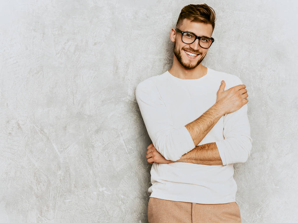 Portrait of handsome smiling hipster lumbersexual businessman model wearing casual summer white clothes. Fashion stylish man posing against gray wall - Фото, зображення