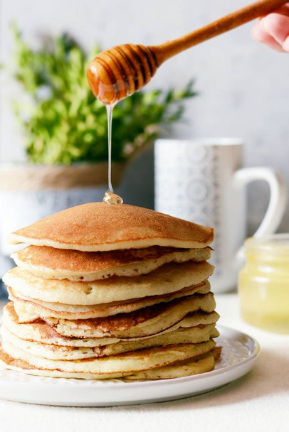 甘い自家製スタックのパンケーキと灰色の背景に朝食に蜂蜜。甘い美しい朝食。ブランチ。家族の朝食。カフェ、レストラン、ファーストフード店、バーの概念 - 写真・画像