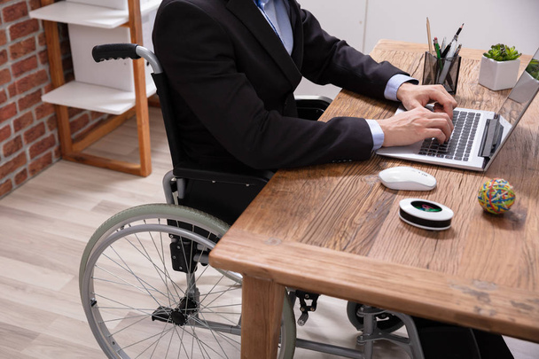 Disabled Businessman Sitting On Wheelchair Using Laptop At Workplace - Foto, Imagem