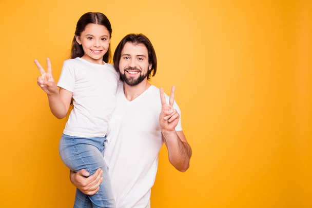 Portrait of her she his he nice cute sweet lovely attractive cheerful people dad holding in hands pre-teen girl showing v-sign isolated over shine vivid pastel yellow background - 写真・画像
