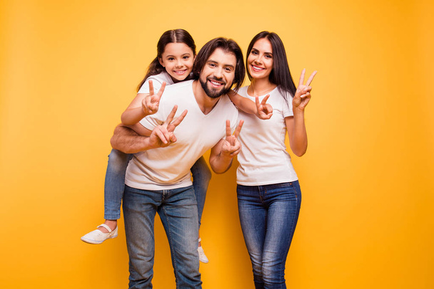 Portrait of nice cute sweet lovely attractive charming cheerful dreamy funny people mom dad pre-teen girl showing v-sign isolated over shine vivid pastel yellow background - 写真・画像