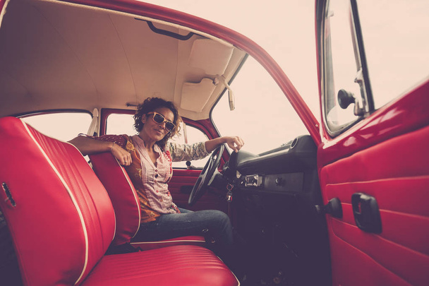 középkorú hölgy vezető pózol, piros legendás retro vintage autó belsejében - Fotó, kép