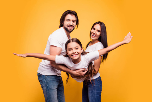 Portrait of nice sweet lovely attractive cheerful cheery people dad daddy mom mommy mum holding in hands carrying pre-teen girl isolated over shine vivid pastel yellow background - Photo, image