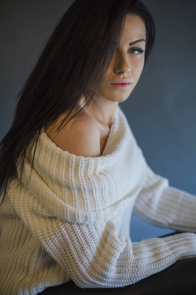 Closeup studio portrait of beauty brunette woman wearing white sweater on grey background - Fotó, kép