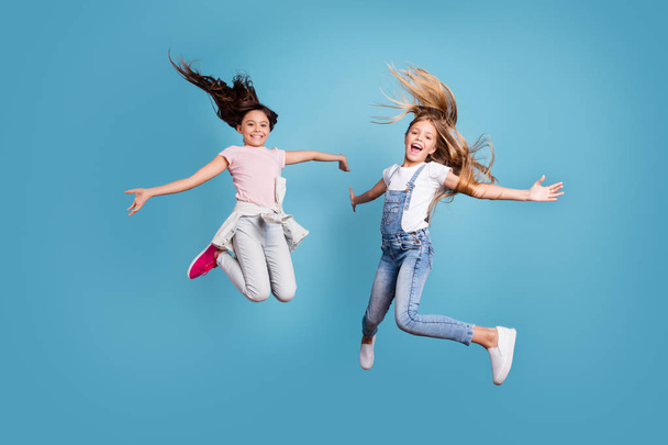 Full length body size view of two people nice lovely attractive cheerful straight-haired pre-teen girls having fun day daydream yes goal achievement free time isolated on blue background. - Zdjęcie, obraz