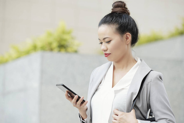Азиатская бизнесвумен читает текстовые сообщения на экране смартфона
 - Фото, изображение