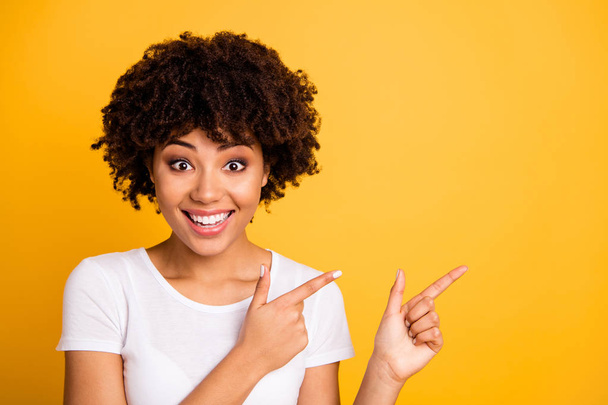 Close-up portrait of her she nice cute lovely charming attractive cheerful cheery wavy-haired girl pointing two fingers aside ad isolated on bright vivid shine yellow background - Foto, imagen