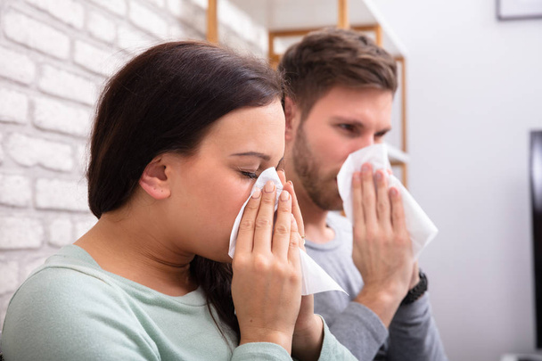 Close-up Of Sick Couple Sneezing In Tissue At Home - Fotó, kép