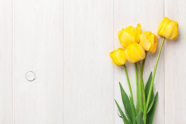 Yellow tulips on wooden table. Top view with space for your text - Fotoğraf, Görsel