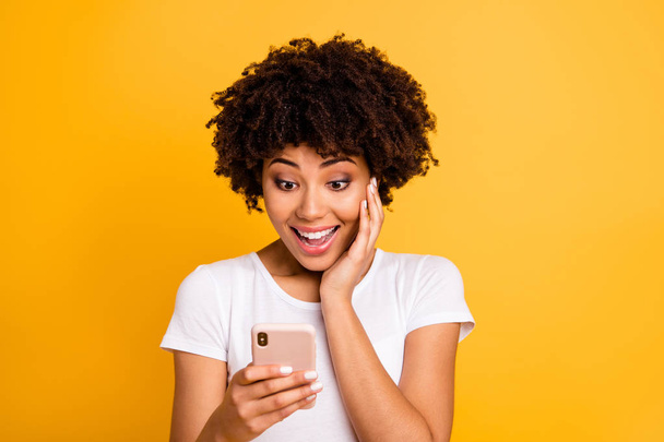 Close-up portrait of her she nice cute attractive lovely charming cheerful amazed wavy-haired lady holding in hands cell reading sms using new app 5g isolated on bright vivid shine yellow background - Fotó, kép