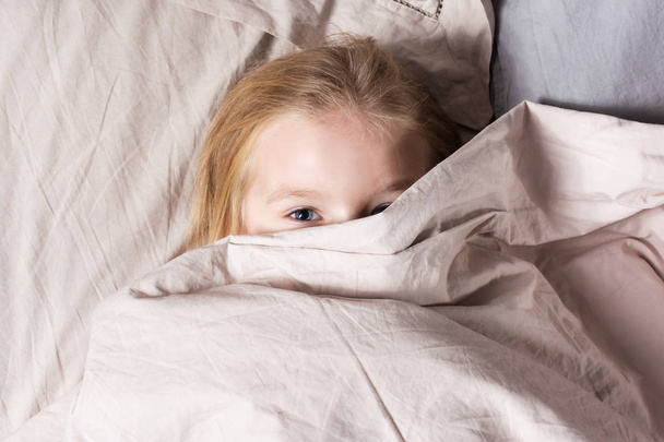 маленька дівчинка з світлим волоссям лежить в ліжку вдома
 - Фото, зображення
