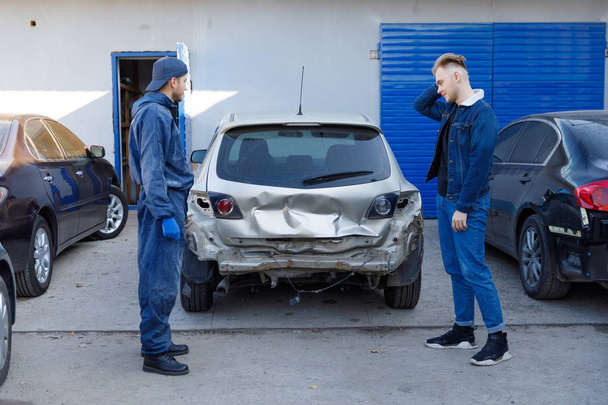 The driver after the accident, emotions, holding his head, the car is broken, at the service station. - Zdjęcie, obraz