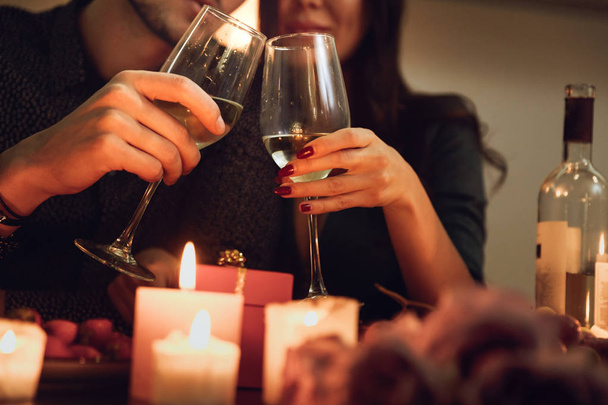 Beautiful passionate couple having a romantic candlelight dinner at home, drinking wine, toasting - Foto, Imagem