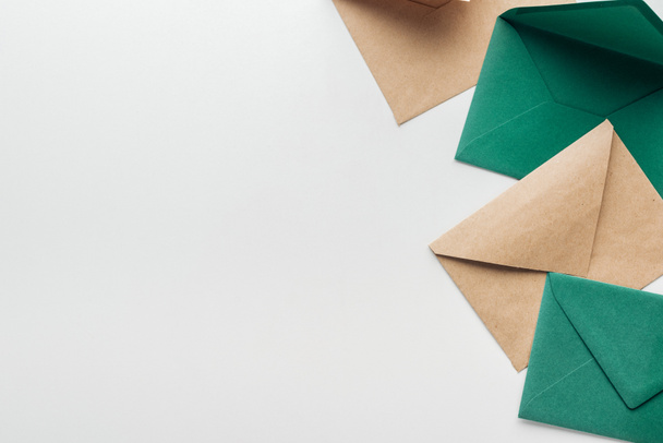 top view of brown and green envelopes on grey background - Φωτογραφία, εικόνα