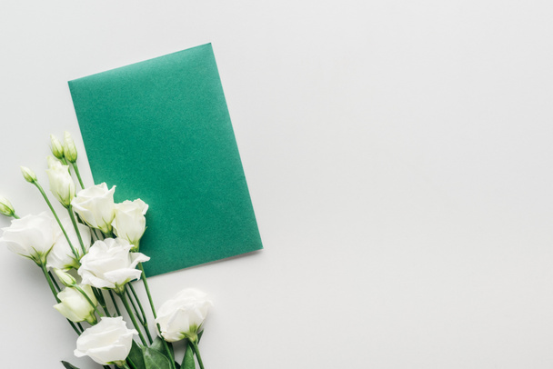 vista superior do envelope verde vazio com flores em fundo cinza
 - Foto, Imagem