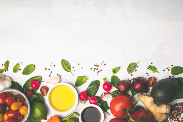 Olijfolie, azijn, groenten en specerijen op witte stenen ondergrond. Salade maken, koken, schoon eten, dieet concept. Vlakke plaat - Foto, afbeelding