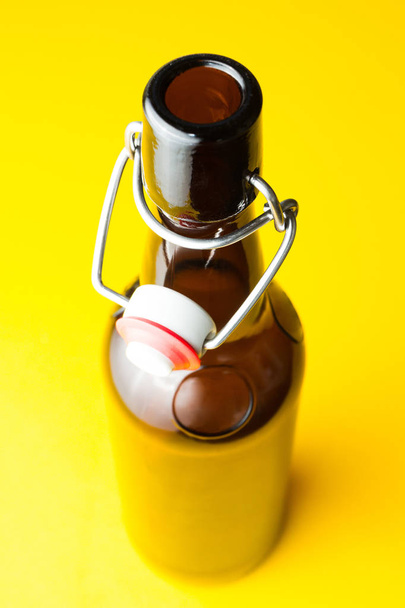 Old brown bottle with beer without a label on a yellow backgroun - Foto, afbeelding