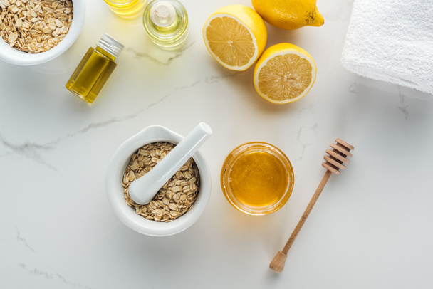 κάτοψη των λιβρών με νιφάδες βρώμης, μπολ με μέλι, τα λεμόνια και διάφορα συστατικά σε λευκή επιφάνεια - Φωτογραφία, εικόνα