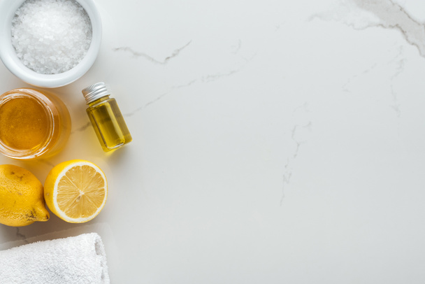 bovenaanzicht van citroenen, honing, zout en andere natuurlijke ingrediënten voor handgemaakte cosmetica op witte ondergrond - Foto, afbeelding