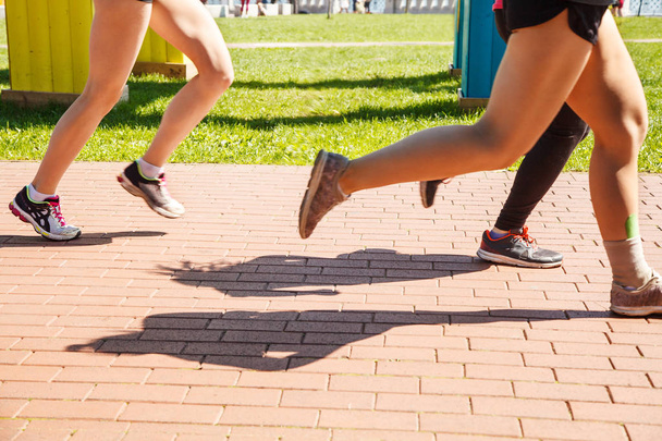 legs of girls running in a sports competition on sunny summer morning - Photo, Image